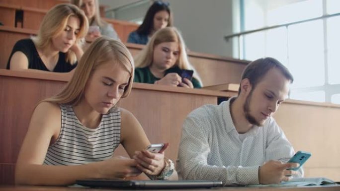讲座期间使用智能手机的多种族学生。年轻人在大学学习时使用社交媒体。