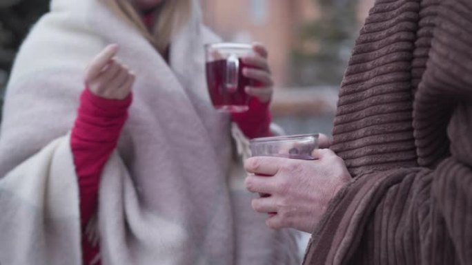 面目全非的高级男人和年轻女人站在户外，端着茶杯。高加索退休人员和亲戚聊天。休闲，生活方式，放松。