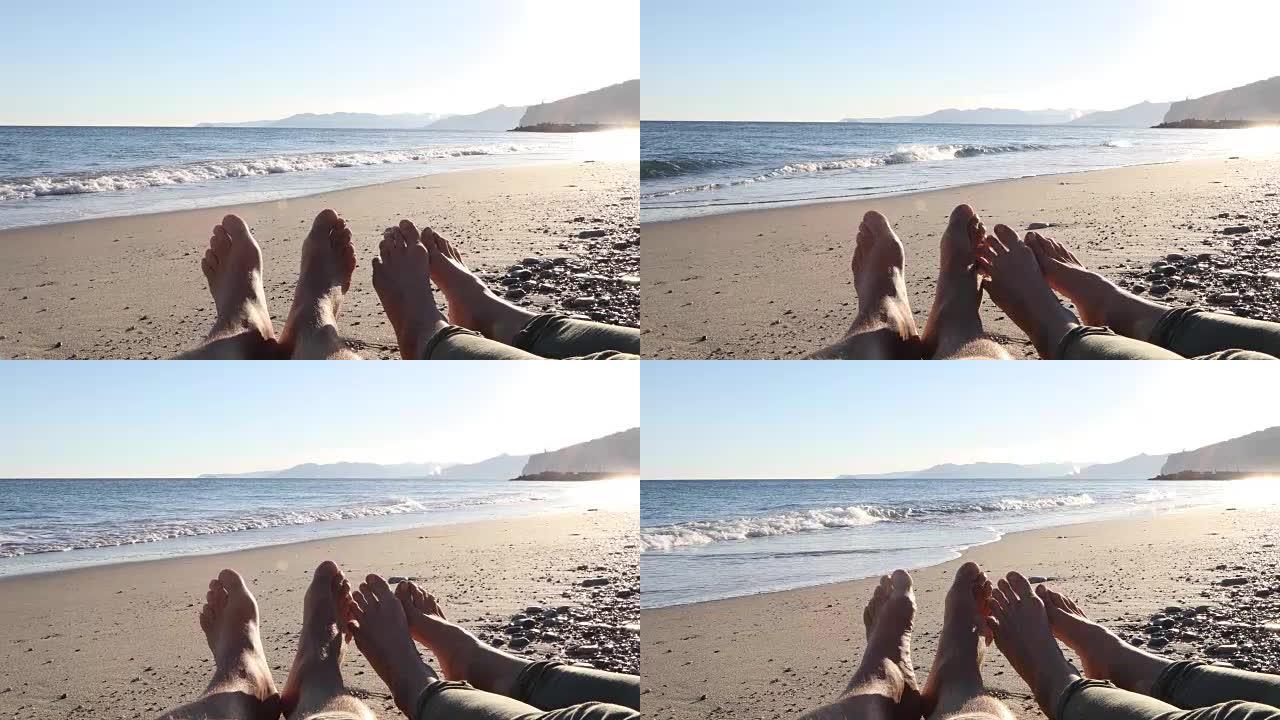 夫妇的双腿在海滩上放松，在后面冲浪