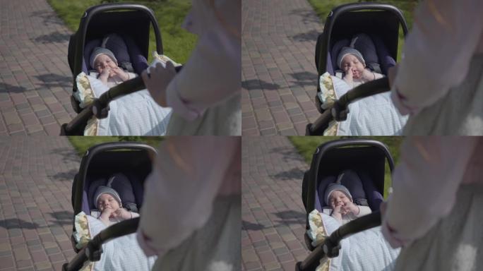 美丽的女人弯下腰在公园的婴儿车上。