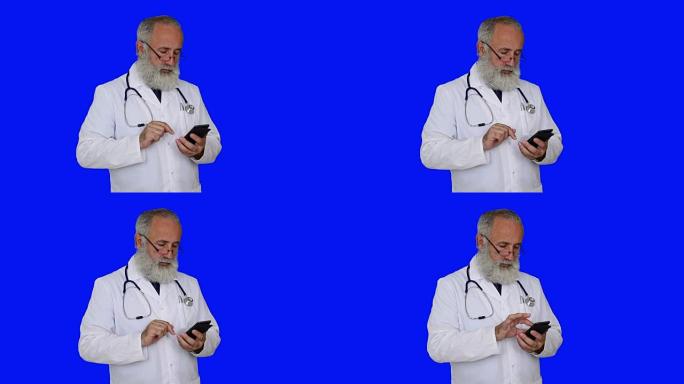 成人高级医生在蓝色背景上使用智能手机