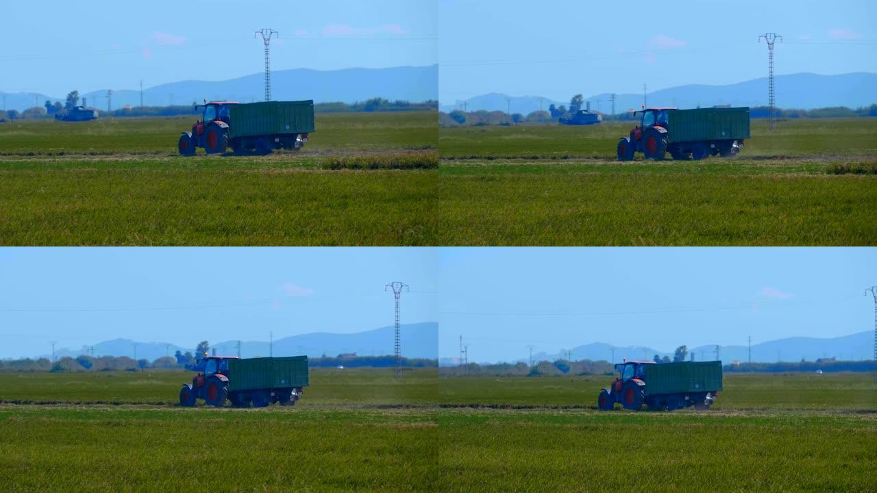 带绿色拖车的红色拖拉机骑在农田上