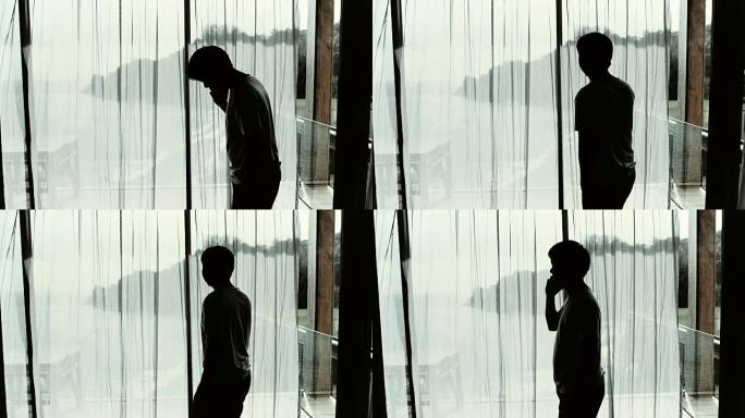 一个年轻人站在窗户旁用手机聊天的特写镜头
