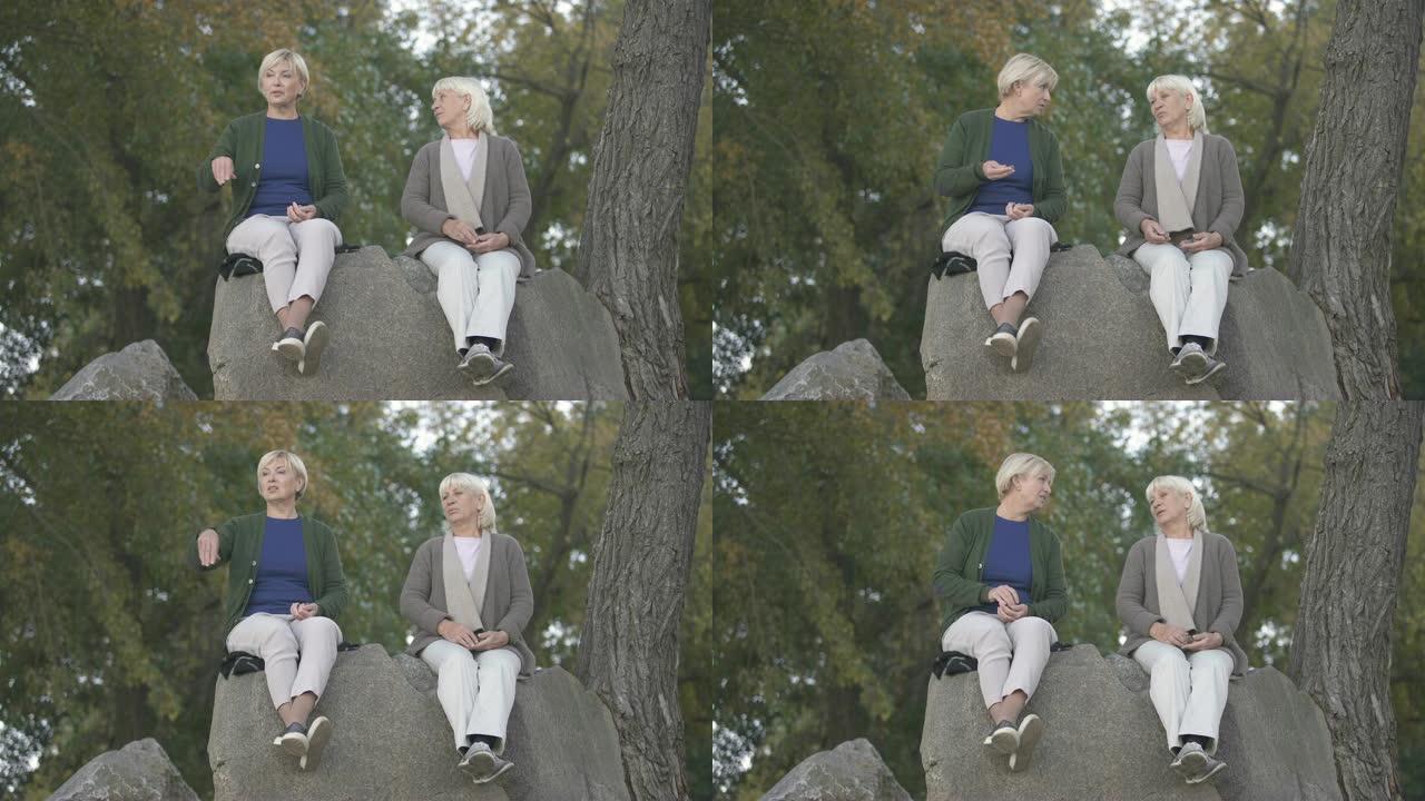 年长的母亲和中年女儿坐在石头上谈论生活