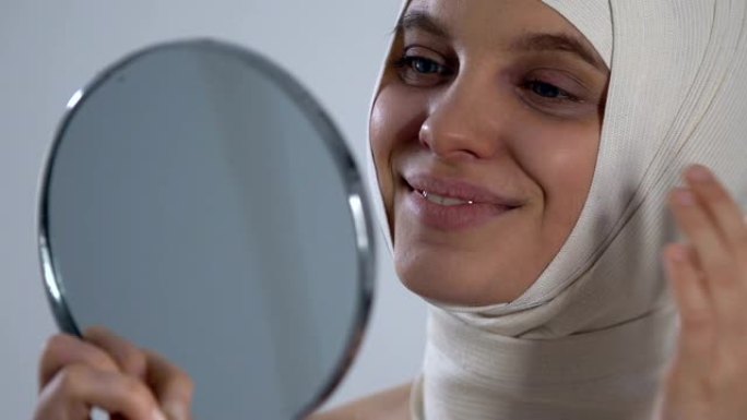 快乐的女孩穿着头巾看着镜子反射，成功的整形手术