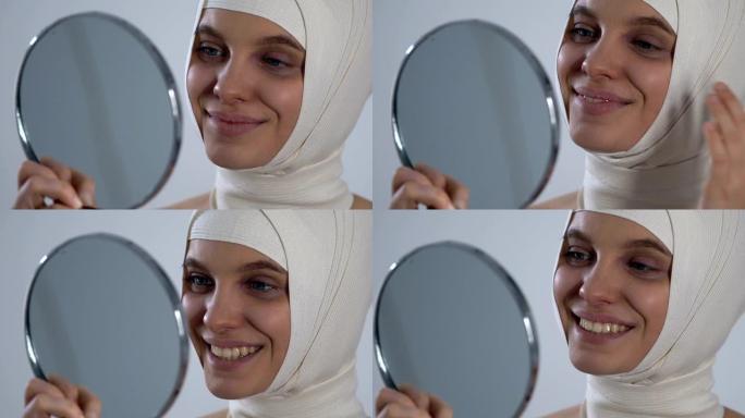 快乐的女孩穿着头巾看着镜子反射，成功的整形手术