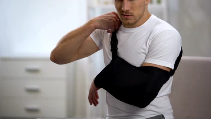 男性患者调整手臂吊带正确位置，创伤后康复