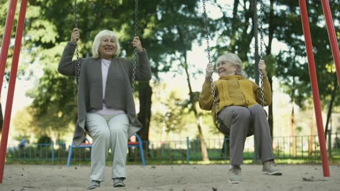 两位高级女士喜欢在公园的秋千上骑行，老年朋友，退休