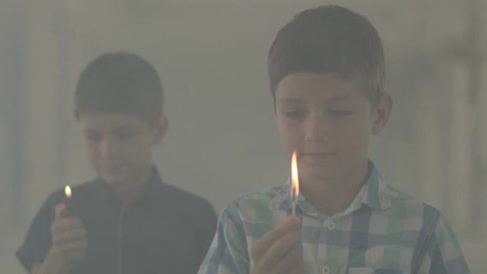 两个小兄弟在黑暗的烟雾弥漫的房间里玩火。