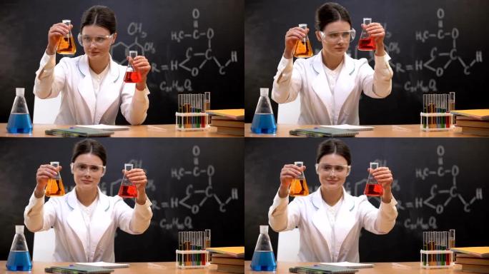 女化学家在烧瓶中向相机展示液体，开发新物质