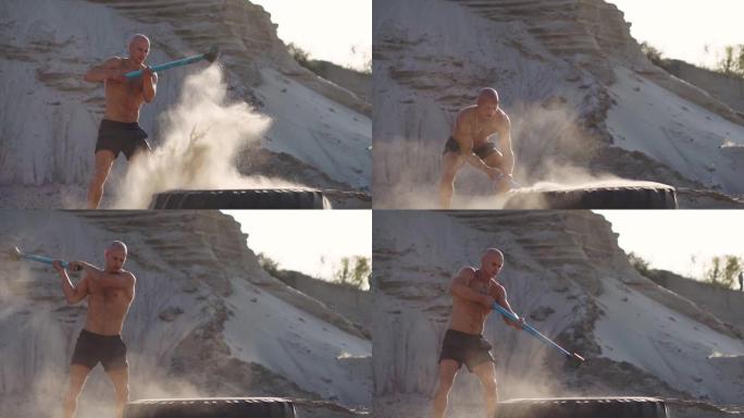 秃头强人在沙山的一个巨大轮子上慢动作击中锤子。摔跤运动员的力量和耐力训练。