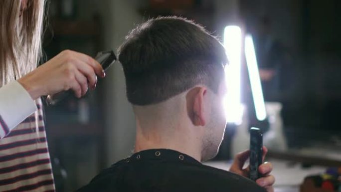 电动剃须刀男性理发。头发修剪器发型的特写。专业理发师用理发推子理发。电动剃须刀男士美发