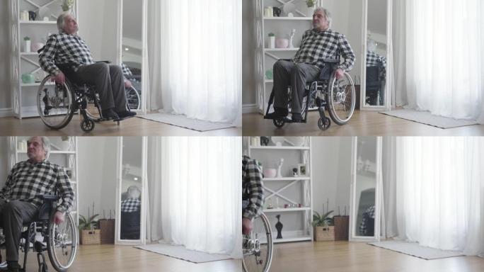 悲伤的白人残疾人老人的肖像从窗户上转动轮椅并滚开。抑郁中的男性退休人员使用设备在室内移动。孤独、残疾