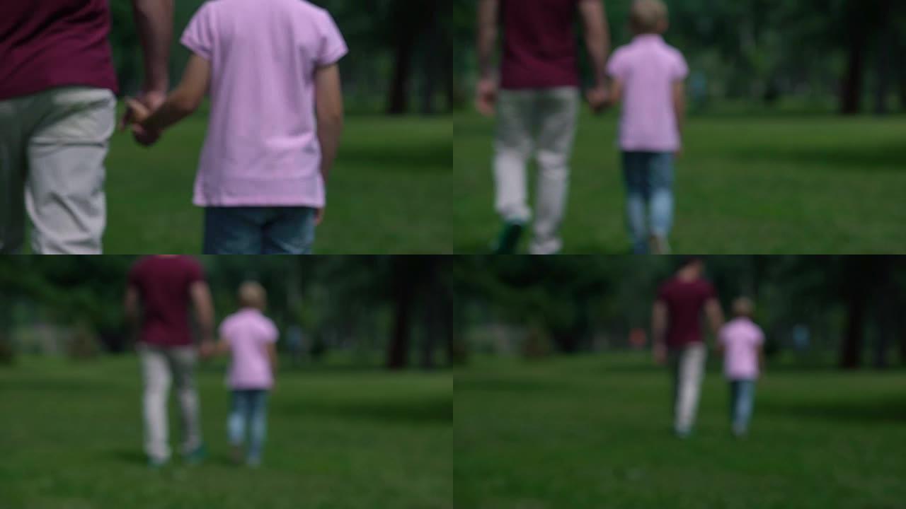 男人和男孩牵着手走开，在公园里的家庭周末，支持