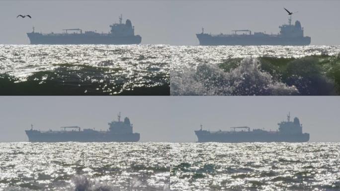 慢动作拍摄了南加州亨廷顿海滩附近的海浪和海鸥，远处地平线上有一艘石油 (石油) 油轮