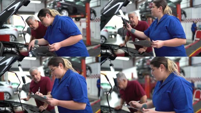 机械师在汽车修理中与她的顾客交谈