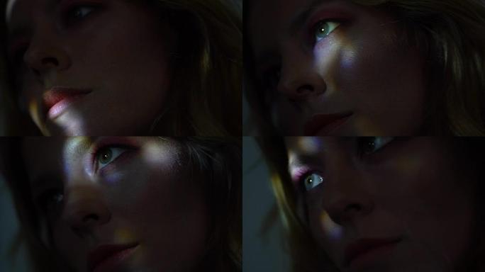 美丽的女性面孔被五颜六色的光束照亮黑暗，特写