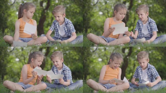 穿着方格衬衫的可爱英俊男孩和长发女孩在公园里看着纸的肖像。