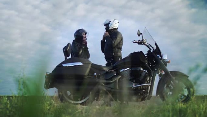 男人用摩托车头盔帮助他的女孩，夫妇准备骑车