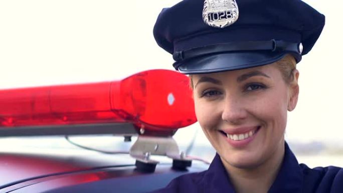 戴着帽子的女警官站在巡逻车附近，微笑着，法律保护
