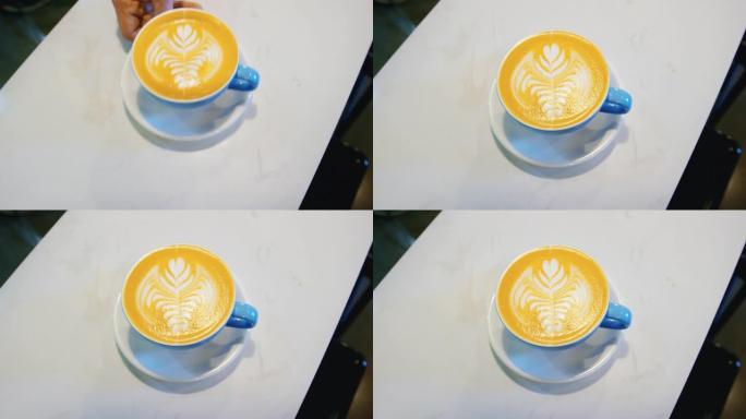 咖啡师在咖啡店的柜台上放了一个小碟和蓝色咖啡杯，上面装有拿铁咖啡