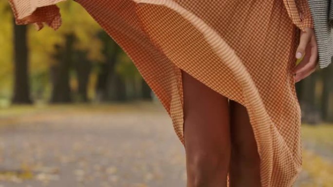 风吹来的芥末酱连衣裙的特写镜头。白人女性的腿从裙子下面出现。电影院4k镜头ProRes总部。