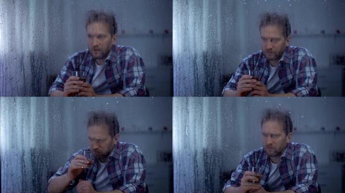 沮丧的男人在雨天独自喝威士忌，思考生活问题