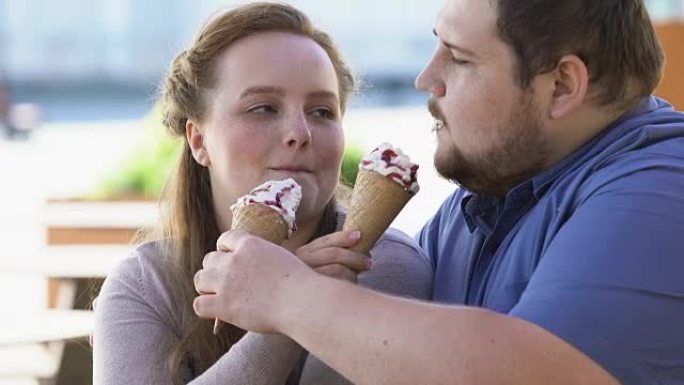 肥胖的情侣分享冰淇淋，含糖甜点，约会调情