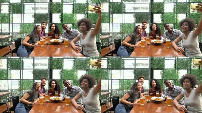一群朋友在酒吧吃喝，同时用智能手机自拍，做鬼脸