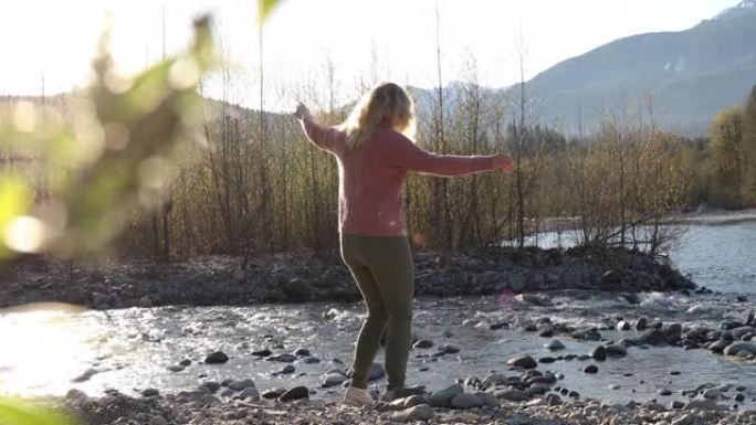成熟的女人在日出时沿着山河行走