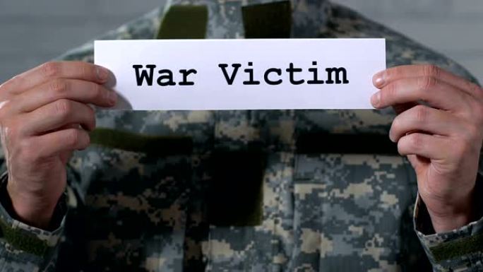 战争受害者在男性士兵手中的纸上写下创伤后应激障碍的概念，特写