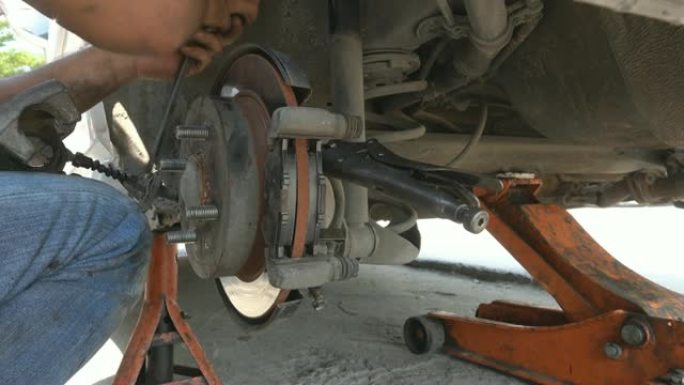 4K: 汽车机械师在汽车车轮制动盘上工作，并在汽车上更换刹车片