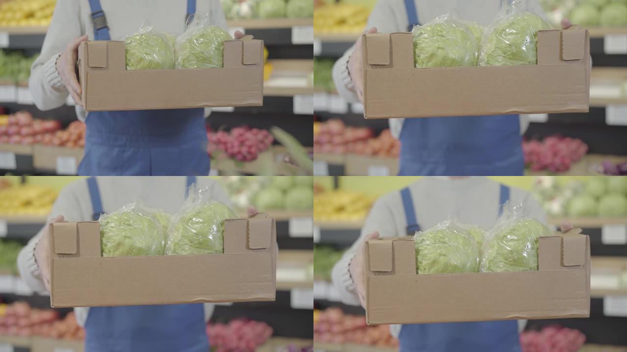 男性高加索人的手伸手带新鲜白菜的盒子。无法辨认的男性员工在杂货店展示素食健康食品。商业，零售，商业，