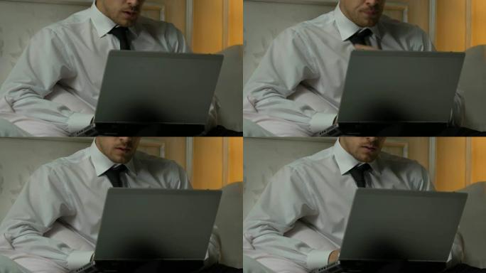 男子在笔记本电脑上打字每周报告，忙碌的记者在床上写文章
