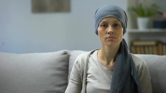 化疗后的女人坐在家里看着相机，背景