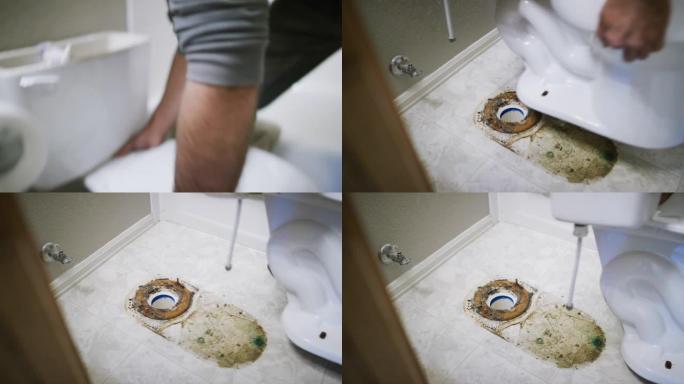 一名穿着凉鞋的高加索修理工抬起瓷器马桶，露出室内家庭浴室下面的肮脏地板和蜡环