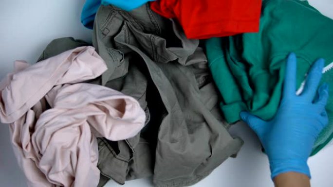 戴上手套，将旧衣服从塑料袋中取出并分类，重复使用