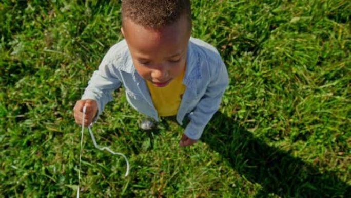 SLO MO CS小男孩在阳光明媚的草地上拿着粉红色的气球