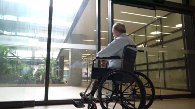 老人坐在轮椅上透过玻璃门眺望的背景图