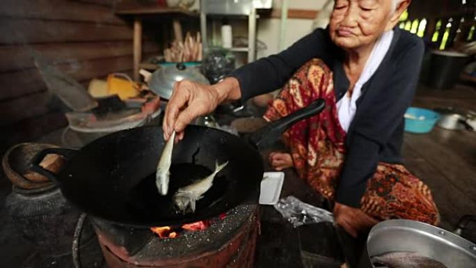 生活方式资深亚洲女性坐在烹饪食物，慢动作