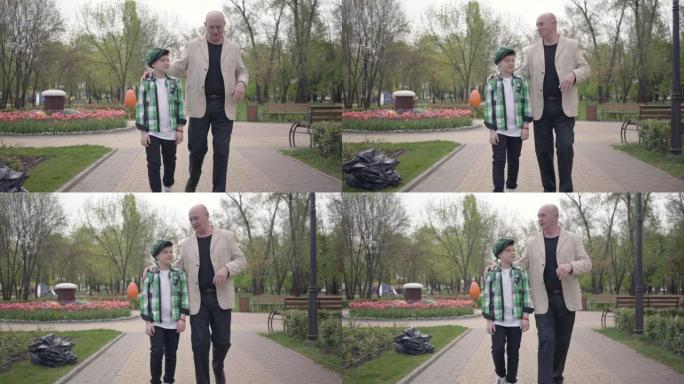 肖像祖父和孙子在公园里走向相机。
