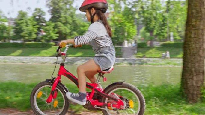 小女孩在公园里骑自行车，然后父母骑着双人自行车