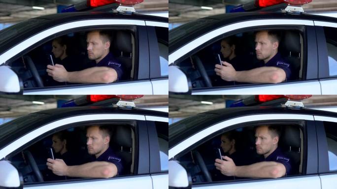 男人和女人警察使用坐在巡逻车中的智能手机，监视城市应用程序