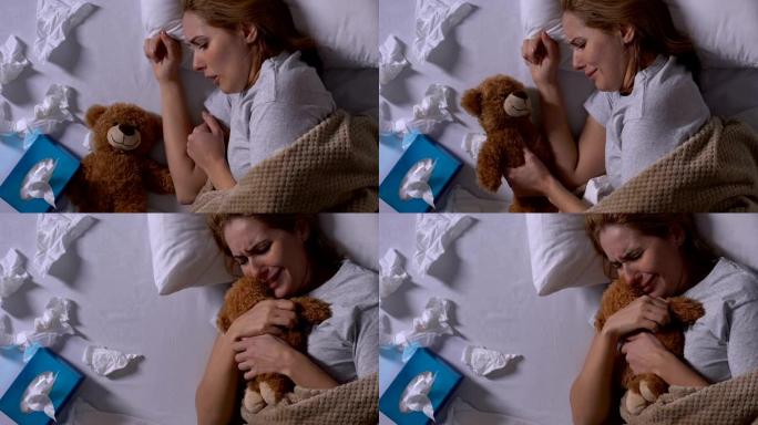 哭泣的女人拥抱泰迪熊，在床上用过的餐巾纸，分手后的孤独