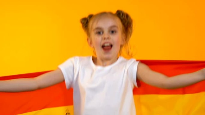 挥舞西班牙国旗的小球迷女孩，为国家运动队加油，支持