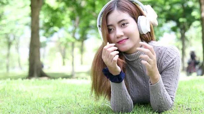 亚洲女性在公园使用平板电脑和耳机放松