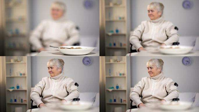 坐在轮椅上的悲伤老妇人在医疗中心看着美味的晚餐，悲伤
