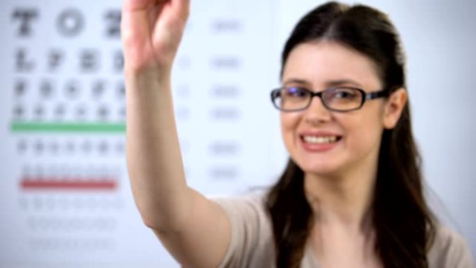 戴眼镜的微笑女人展示隐形眼镜盒，推荐新技术