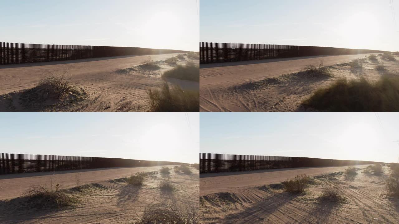 在一个阳光明媚的下午，多莉的空中无人机拍摄了墨西哥和美国之间的钢板条边界墙 (在美国一侧) 前的一条
