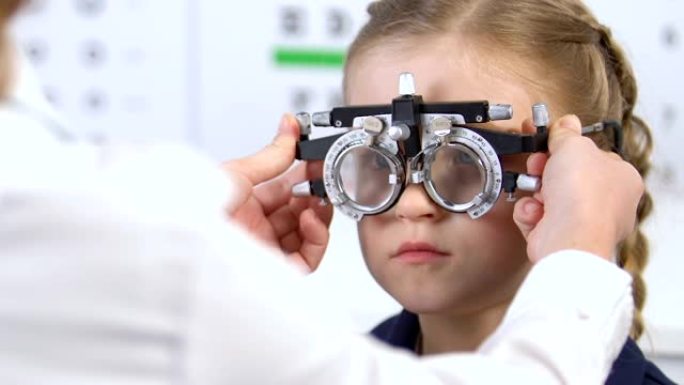 验光师使用光学试验架检查女孩的视力，视力检查